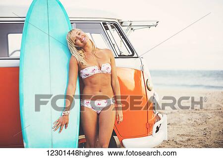 Stock Photograph - Beach Lifestyle, Beautiful Surfer Girl On The Beach At Sunset With Classic Vintage Surf Van. Fotosearch