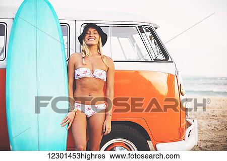 Stock Photograph - Beach Lifestyle, Beautiful Surfer Girl On The Beach At Sunset With Classic Vintage Surf Van. Fotosearch