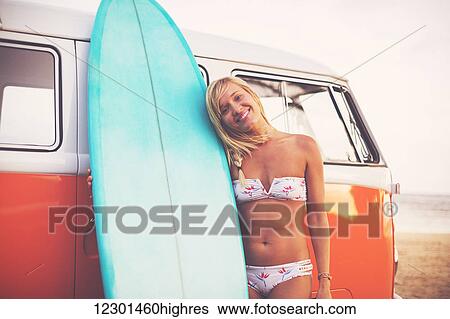 Stock Photograph - Beach Lifestyle, Beautiful Surfer Girl On The Beach At Sunset With Classic Vintage Surf Van. Fotosearch