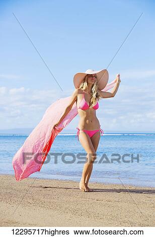 Stock Photograph - Beautiful Woman Walking On Tropical Beach With Sarong Blowing In The Wind. Fotosearch