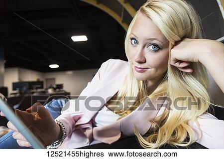 Stock Photograph - Beautiful young millennial businesswoman with long blond hair posing for the camera in the workplace; Sherwood Park, Alberta, Canada. Fotosearch
