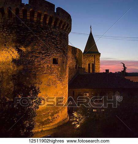 Stock Photograph - Belgrade Fortress at dusk and the round stone wall illuminated with light and a tower with cross; Belgrade, Vojvodina, Serbia. Fotosearch