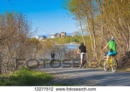 Stock Image - Bicyclists on the Tony Knowles Coastal Trail near downtown Anchorage, Alaska, Spring. Fotosearch