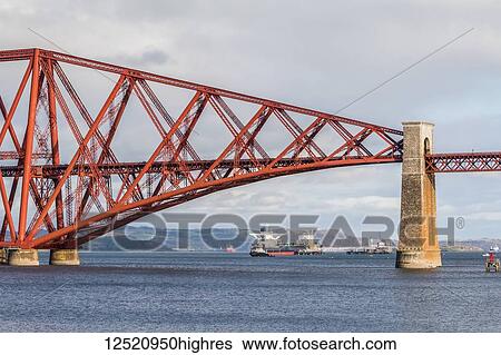 Stock Photograph - Boat sailing under the River Forth rail bridge on a bright day; Scotland. Fotosearch