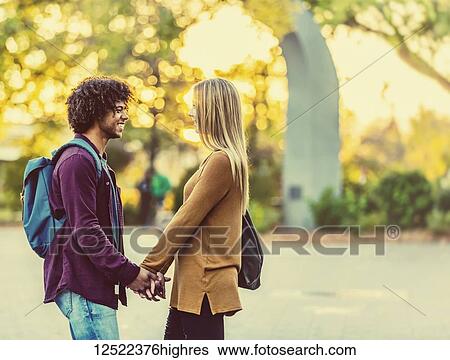 Boyfriend and girlfriend standing and looking at each other while holding hands on the grounds of a university campus at sunset; Edmonton, Alberta, Canada View Large Photo Image Stock Photograph - Boyfriend and girlfriend standing and looking at each other while holding hands on the grounds of a university campus at sunset; Edmonton, Alberta, Canada. Fotosearch