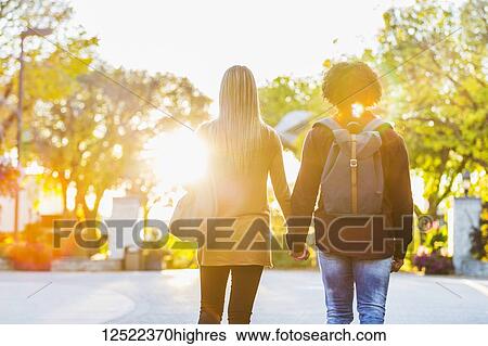 Boyfriend and girlfriend walking away from the camera and holding hands on the university campus at sunset; Edmonton, Alberta, Canada View Large Photo Image Stock Photograph - Boyfriend and girlfriend walking away from the camera and holding hands on the university campus at sunset; Edmonton, Alberta, Canada. Fotosearch