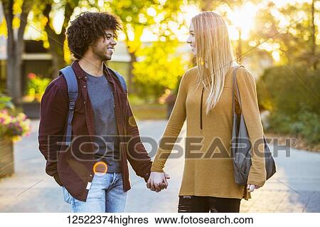 Boyfriend and girlfriend walking, talking and holding hands on the university campus at sunset; Edmonton, Alberta, Canada View Large Photo Image Stock Photograph - Boyfriend and girlfriend walking, talking and holding hands on the university campus at sunset; Edmonton, Alberta, Canada. Fotosearch