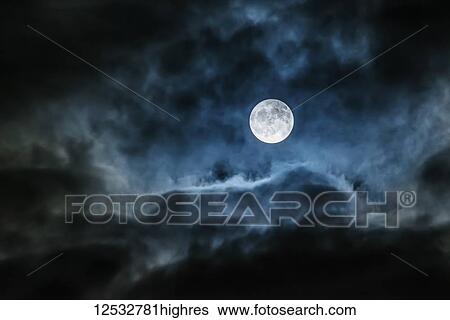 Stock Photograph - Bright full moon glowing in a cloudy sky; Ontario, Canada. Fotosearch