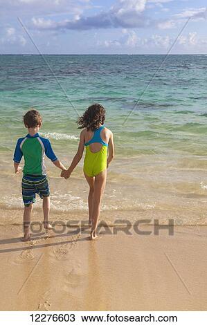 Brother and sister holding hands and walking in to the water on a beach; Kailua, Island of Hawaii, Hawaii, United States of America View Large Photo Image Stock Image - Brother and sister holding hands and walking in to the water on a beach; Kailua, Island of Hawaii, Hawaii, United States of America. Fotosearch