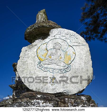 Stock Photograph - Buddhist symbol etched in a rock against a blue sky; Sikkim, India. Fotosearch