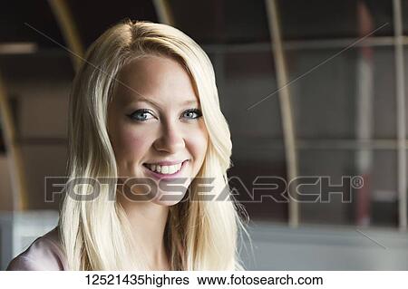 Stock Photograph - Business portrait of a beautiful young millennial business woman with long blond hair in the workplace; Sherwood Park, Alberta, Canada. Fotosearch