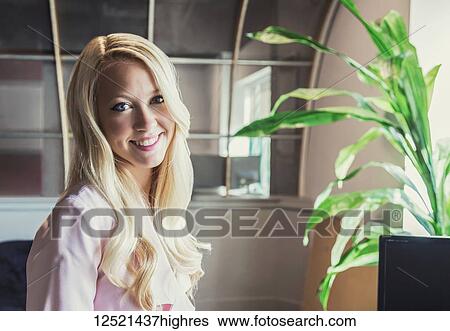 Stock Photograph - Business portrait of a beautiful young millennial business woman with long blond hair in the workplace; Sherwood Park, Alberta, Canada. Fotosearch