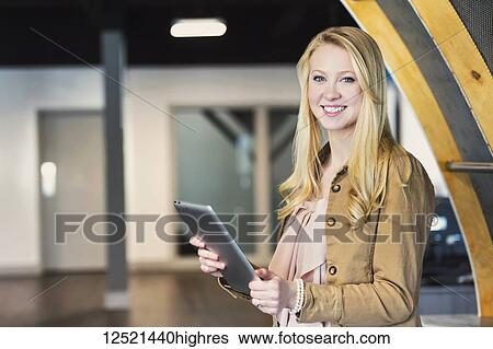 Stock Photograph - Business portrait of a beautiful young millennial professional using technology in the workplace; Sherwood Park, Alberta, Canada. Fotosearch
