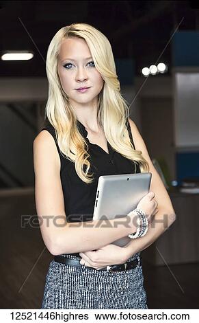 Business portrait of a beautiful young millennial businesswoman with long blond hair holding a tablet and posing for the camera in the workplace; Sherwood Park, Alberta, Canada View Large Photo Image Stock Photograph - Business portrait of a beautiful young millennial businesswoman with long blond hair holding a tablet and posing for the camera in the workplace; Sherwood Park, Alberta, Canada. Fotosearch