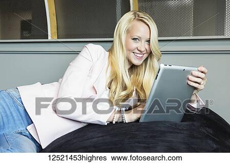 Stock Photograph - Business portrait of a beautiful young millennial businesswoman with long blond hair holding a tablet and posing for the camera in the workplace; Sherwood Park, Alberta, Canada. Fotosearch