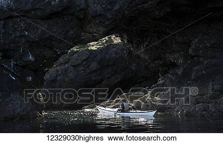 Stock Photograph - Canoeing along dark rocks of the shoreline in Kachemak Bay State Park; Alaska, United States of America. Fotosearch