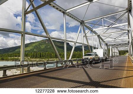 Car and trailer crossing a metal bridge over the Racing River, Alaska Highway, West of Fort Nelson, British Columbia, Canada, Summer View Large Photo Image Stock Photo - Car and trailer crossing a metal bridge over the Racing River, Alaska Highway, West of Fort Nelson, British Columbia, Canada, Summer. Fotosearch