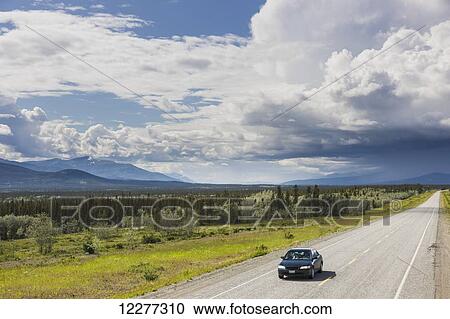 Car driving on the Alaska Highway with stormy clouds overhead, west of Whitehorse, Yukon Territory, Canada, Summer View Large Photo Image Stock Image - Car driving on the Alaska Highway with stormy clouds overhead, west of Whitehorse, Yukon Territory, Canada, Summer . Fotosearch