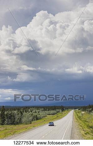 Car on the Alaska Highway with rainclouds in the background, Yukon Territory, Canada, Summer View Large Photo Image Picture - Car on the Alaska Highway with rainclouds in the background, Yukon Territory, Canada, Summer. Fotosearch