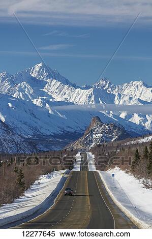 Stock Photography - Car on the Glenn Highway with Lion's Head and the Talkeetna Mountains in the background, Southcentral Alaska, USA, Winter. Fotosearch