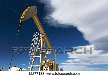 Close up and low angle of pumpjack with dramatic clouds in the blue sky; Alberta, Canada View Large Photo Image Stock Photo - Close up and low angle of pumpjack with dramatic clouds in the blue sky; Alberta, Canada. Fotosearch