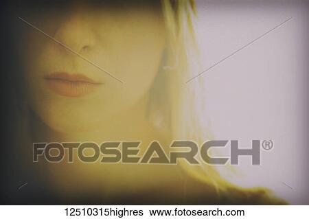 Stock Photograph - Close-up of a portion of a young woman's face showing her nose, lips and long blond hair. Fotosearch