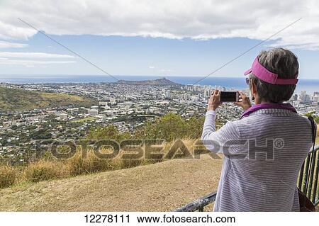 Close up of a tourist taking a photo with a smart phone of downtown Honolulu and Diamond Head; Honolulu, Oahu, Hawaii, United States of America View Large Photo Image Stock Image - Close up of a tourist taking a photo with a smart phone of downtown Honolulu and Diamond Head; Honolulu, Oahu, Hawaii, United States of America. Fotosearch