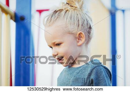 Stock Photograph - Close-up of a young girl with blond hair playing in a playground on a warm fall day; Spruce Grove, Alberta, Canada. Fotosearch