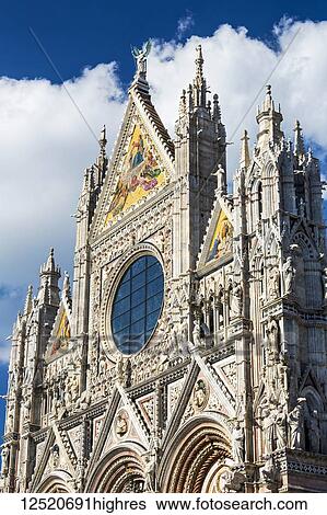 Stock Photograph - Close-up of decorative and ornate facade of Siena Cathedral with blue sky and clouds; Siena, Tuscany, Italy. Fotosearch