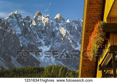 Stock Photograph - Close-up of wooden chalet with flower box and rugged mountain range in the background with blue sky; Grainau, Bavaria, Germany. Fotosearch