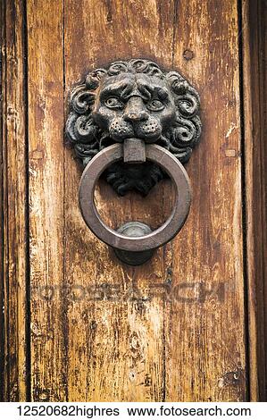 Stock Photograph - Close-up of wooden door knocker with metal ring on old wooden door; Siena, Tuscany, Italy. Fotosearch