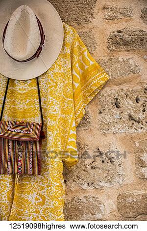 Clothes and accessories hanging on display against a stone wall; Alcudia, Mallorca, Balearic Islands, Spain View Large Photo Image Stock Photograph - Clothes and accessories hanging on display against a stone wall; Alcudia, Mallorca, Balearic Islands, Spain. Fotosearch