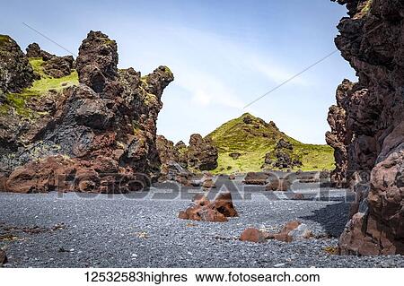 Stock Photograph - Colourful lava rock formations scattered across the black sand beach in Snaefellsjokull National Park; Iceland. Fotosearch
