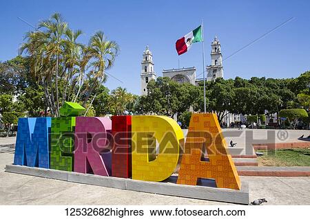 Stock Photograph - Colourful Merida sign with Mexican flag and Cathedral Of San Ildefonso in the background; Merida, Yucatan, Mexico. Fotosearch