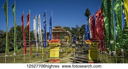 Stock Photograph - Colourful prayer flags line a path leading to a Buddhist building; Kaluk, Sikkim, India. Fotosearch
