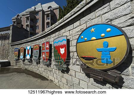 Stock Photograph - Colourful symbolic crests and artwork on a stone wall along a walkway representing the Canadian Provinces; Victoria, British Columbia, Canada. Fotosearch
