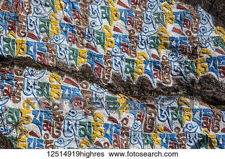 Stock Photograph - Colourful Tibetan script on a boulder in the Nepalese Himalayas; Nepal. Fotosearch