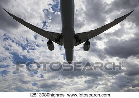 Stock Photograph - Commercial airliner flying in the clouds; Georgetown, Ontario, Canada. Fotosearch