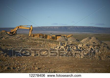 Stock Photograph - Construction equipment on the edge of town with Mount Pelly in the background; Cambridge Bay, Nunavut, Canada. Fotosearch