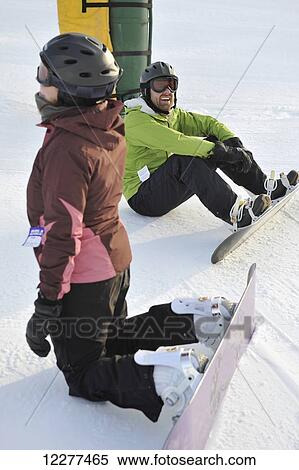 Stock Photography - Couple relax while snowboarding at Hilltop Ski Area in Anchorage, Alaska. Fotosearch