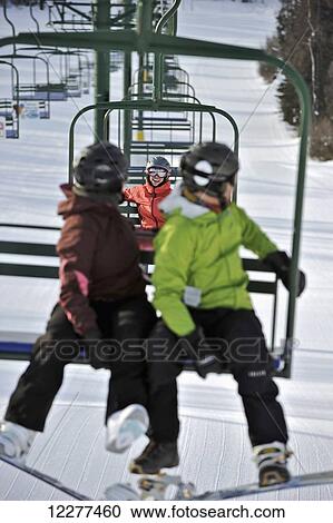 Stock Image - Couple ride the chair lift at Hilltop Ski Area in Anchorage, Alaska. Fotosearch