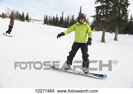 Picture - Couple snowboarding at Hilltop Ski Area in Anchorage, Alaska. Fotosearch
