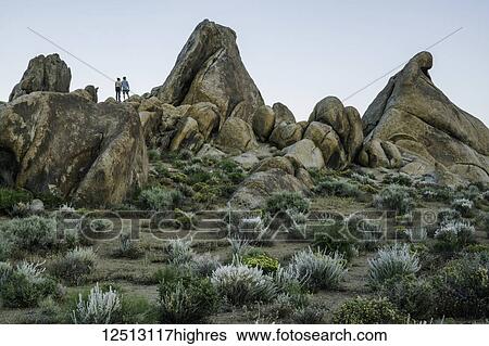 Stock Photograph - Couple standing on rocks of the Alabama Hills after sunset; California, United States of America. Fotosearch