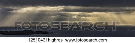 Crepuscular rays shining through the storm clouds onto the ocean water; Isle of Skye, Highlands, Scotland View Large Photo Image Stock Photograph - Crepuscular rays shining through the storm clouds onto the ocean water; Isle of Skye, Highlands, Scotland. Fotosearch