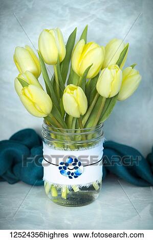 Stock Photograph - Cut tulips in a decorative glass jar with a pendant. Fotosearch