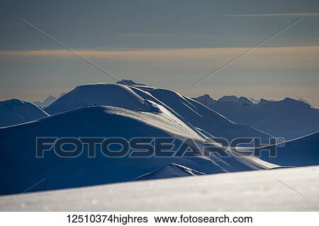 Stock Photograph - Dramatic landscape of the snow covered mountain ranges with shadows and sparkling snow at sunset; Haines, Alaska, United States of America. Fotosearch