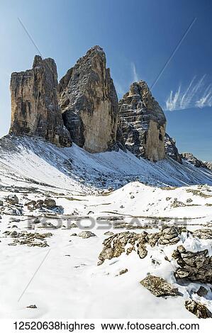 Stock Photograph - Dramatic mountain spires on top of snow-covered rocky plateau and blue sky; Sesto, Bolzano, Italy. Fotosearch