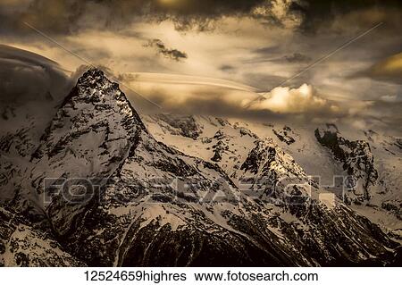 Dramatic view of snow-covered Caucasus Mountains and glowing clouds, Dombay region; Karachaevo-Cherkesskaya Republic, Russia View Large Photo Image Stock Photograph - Dramatic view of snow-covered Caucasus Mountains and glowing clouds, Dombay region; Karachaevo-Cherkesskaya Republic, Russia. Fotosearch