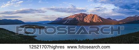 Stock Photograph - Dusky light illuminates the mountains surrounding Tagish Lake in the Yukon; Carcross, Yukon Territory, Canada. Fotosearch