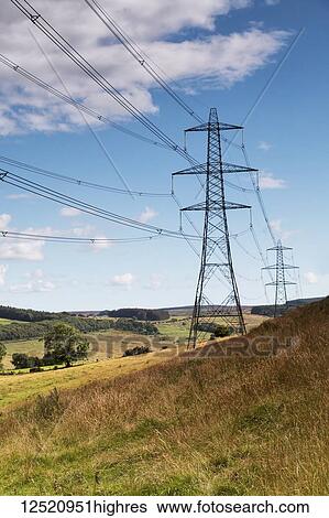 Stock Photograph - Electricity pylons within beautiful countryside and blue sky with whispy clouds; England. Fotosearch